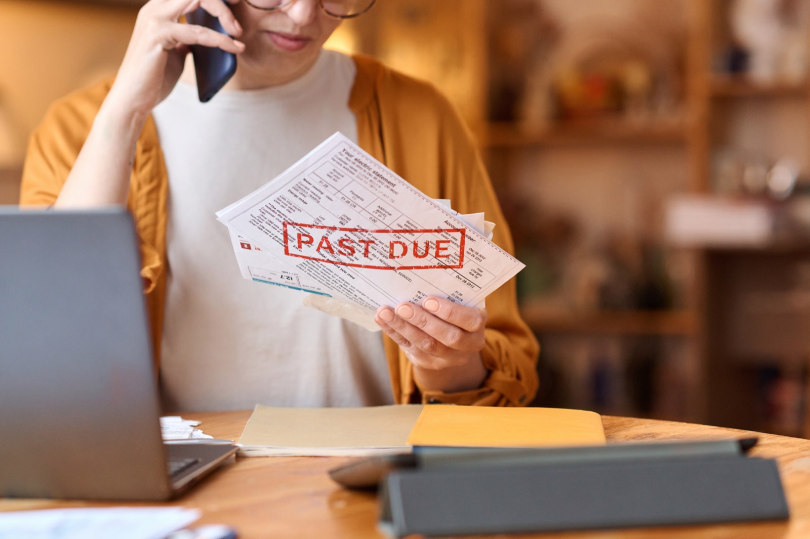 Borrower on the phone holding an invoice stamped past due.